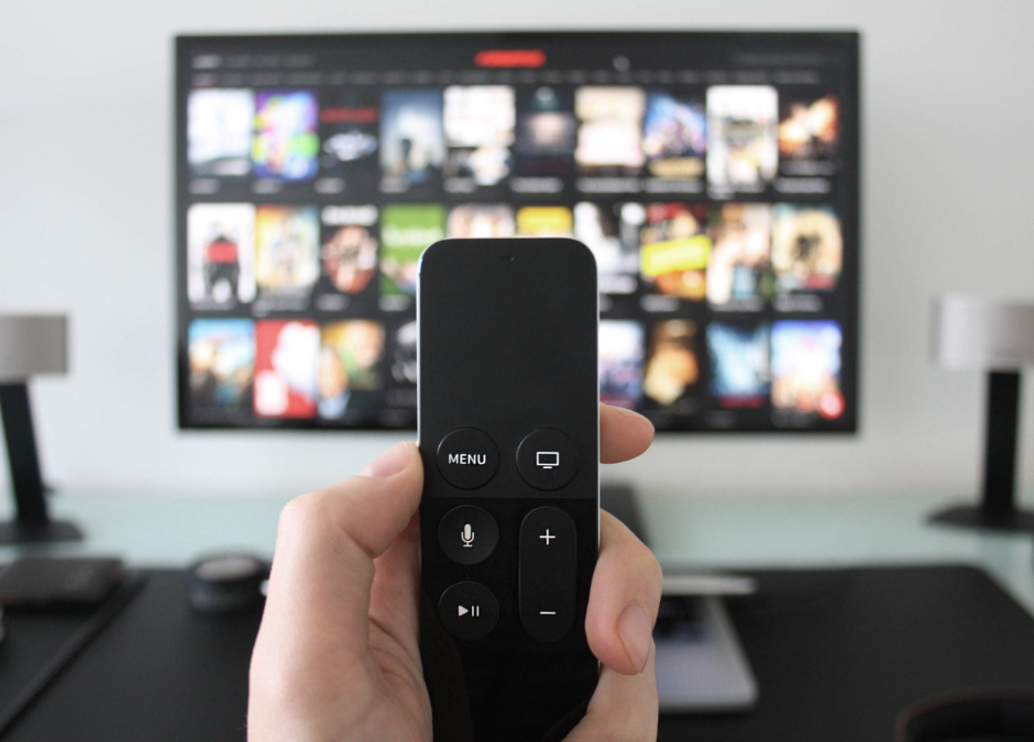 hand holding remote in front of streaming tv